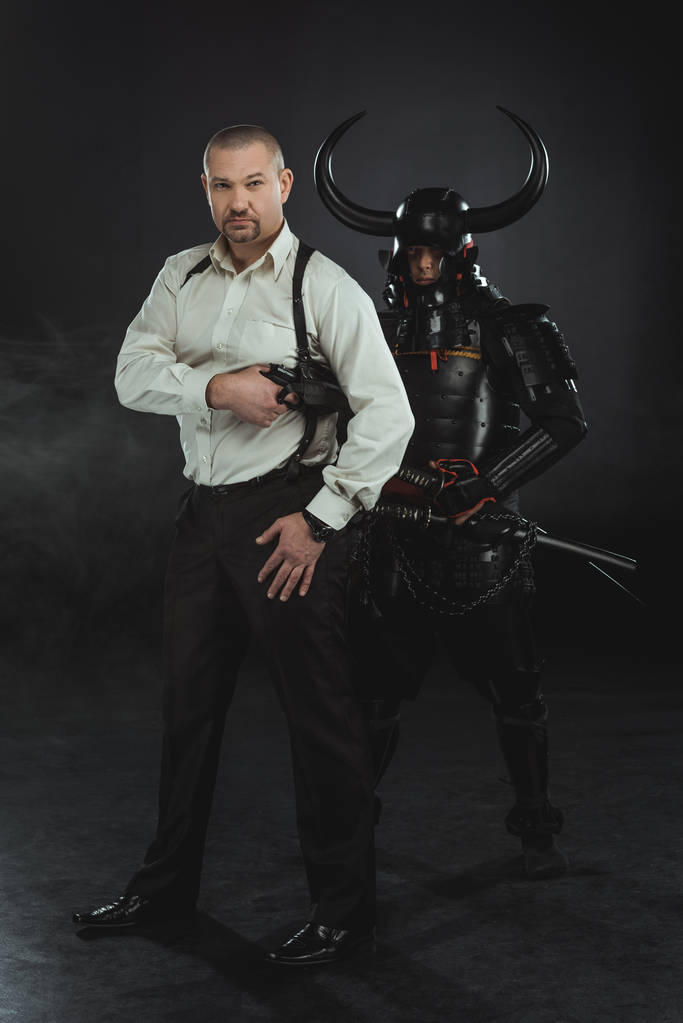 Mann mit Waffe und Samurai hinter sich auf schwarz - Foto, Bild