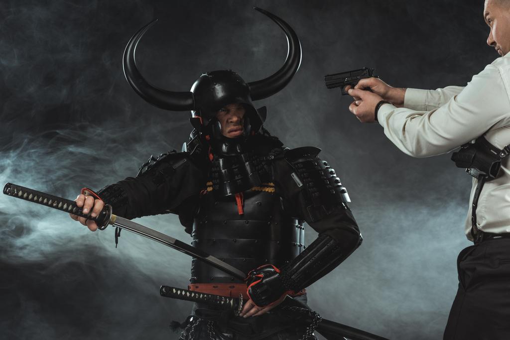 moderner Mann, der mit Gewehr auf Samurai zielt, während er sein Schwert zückt - Foto, Bild