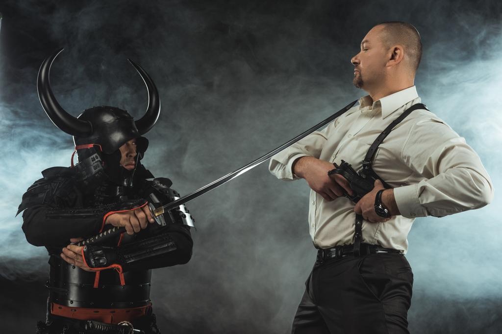 samurai blindado com katana pronto para matar o homem enquanto ele tira sua arma
 - Foto, Imagem