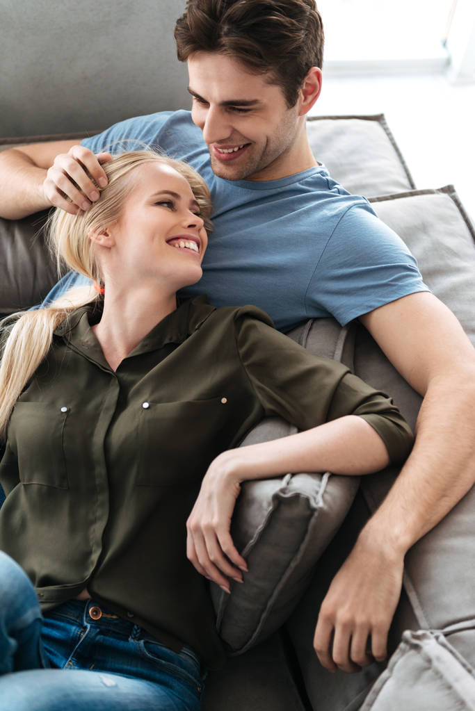 Щасливі коханці лежать на дивані і обіймаються у вітальні
 - Фото, зображення