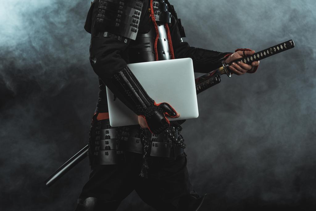 煙で暗い背景に剣を出してのラップトップで伝統的な鎧武士のクロップ撮影 - 写真・画像