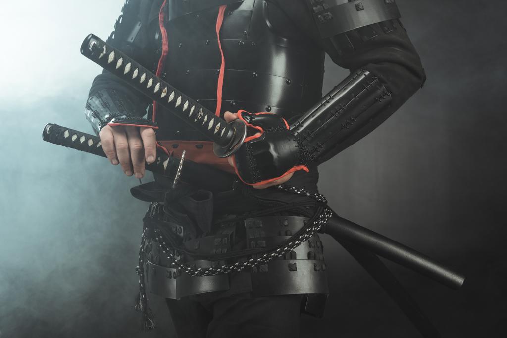 recortado disparo de samurai en armadura con espadas sobre fondo oscuro con humo
 - Foto, Imagen