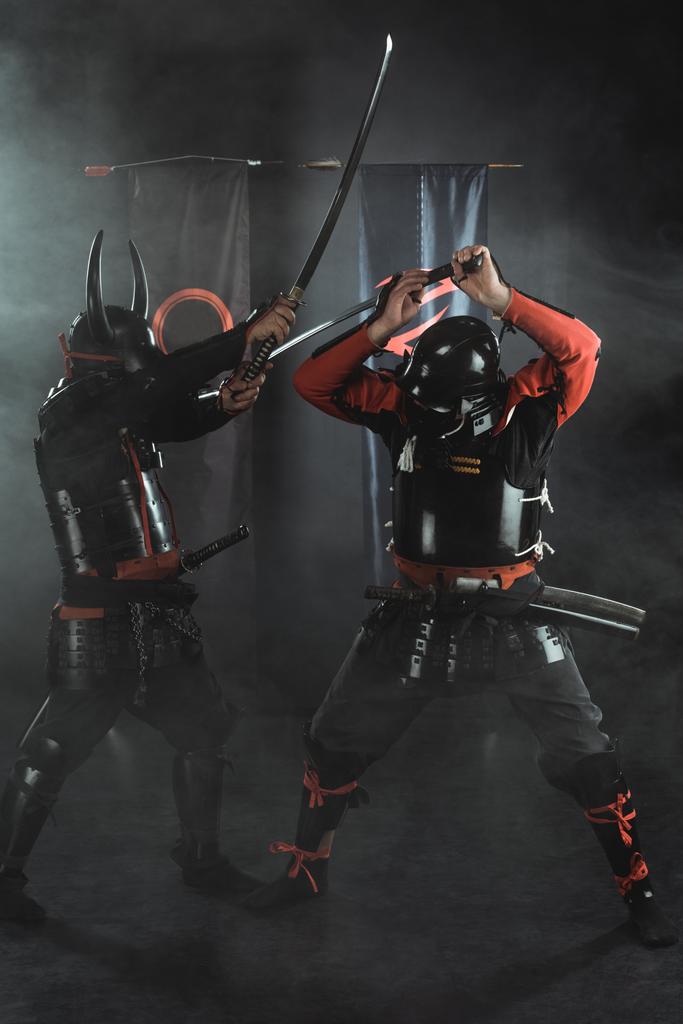 samurai blindados tradicionales luchando con espadas sobre negro
 - Foto, Imagen