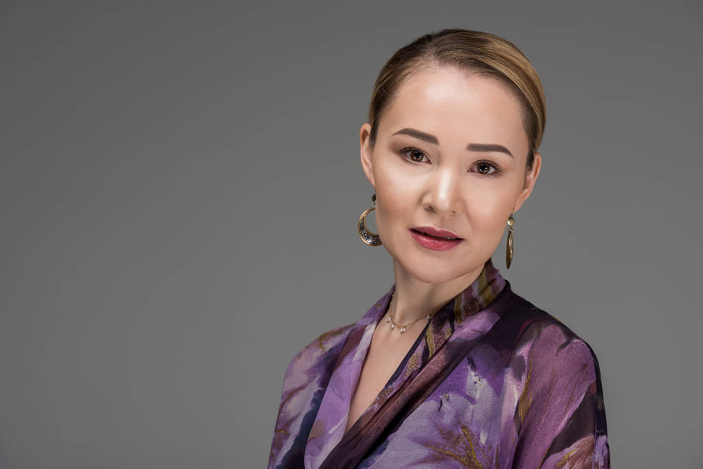 retrato de elegante mulher kazakh elegante olhando para a câmera isolada em cinza
 - Foto, Imagem