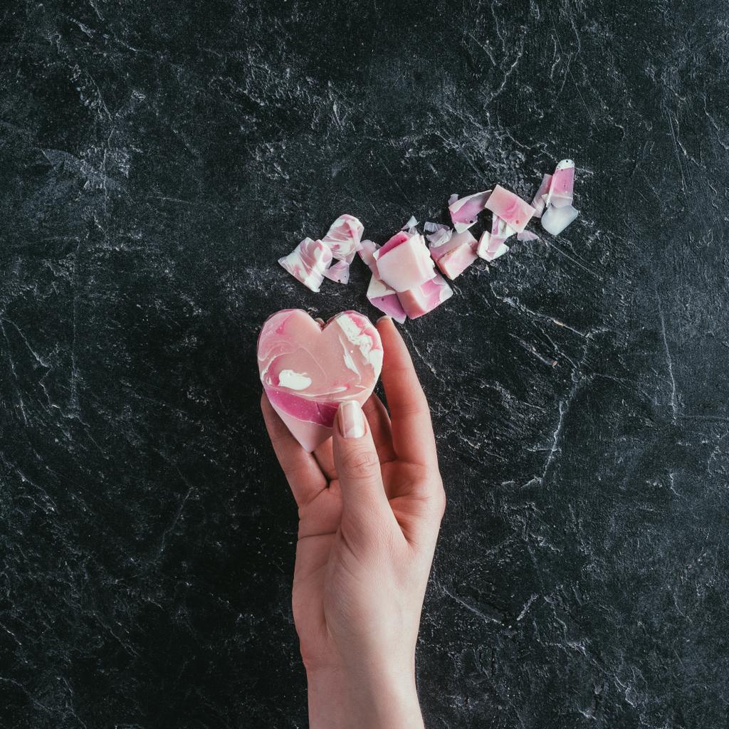 vista recortada de la mano femenina con jabón en forma de corazón rosa en la superficie de mármol negro
  - Foto, Imagen