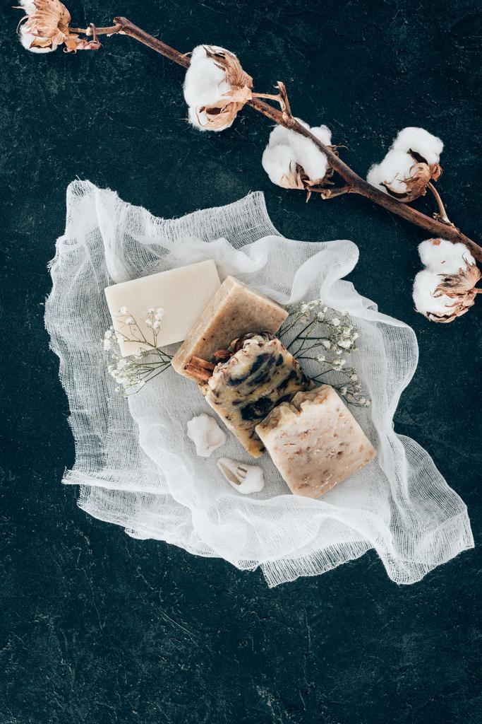 top view of natural homemade soap and dried cotton flowers on gauze on marble surface - Photo, Image