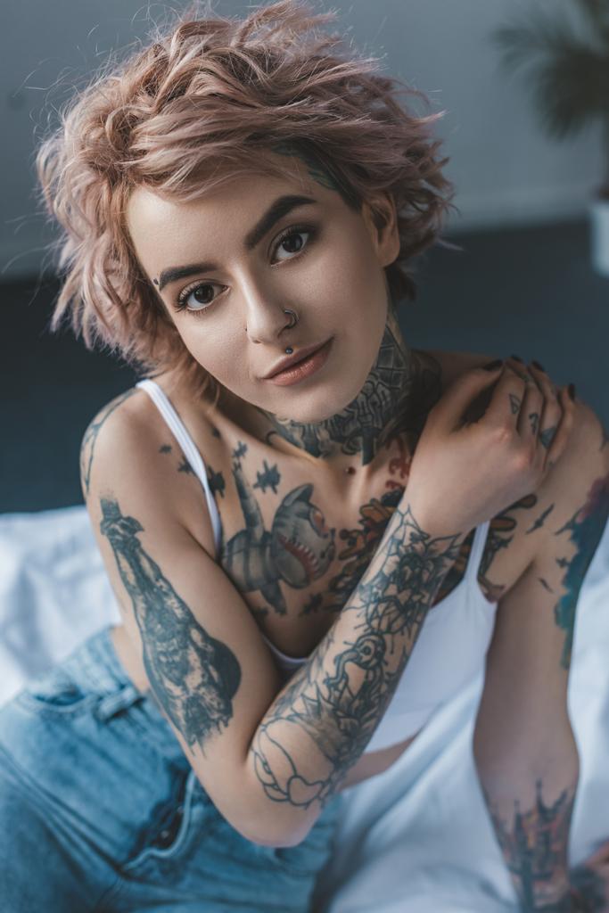 portrait of tender tattooed girl with pink hair in bedroom - Photo, Image