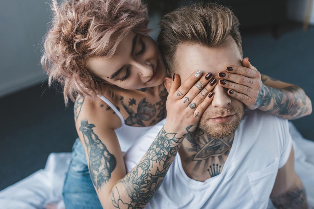πανέμορφο τατουάζ κορίτσι κλείνοντας τα μάτια του φίλου της  - Φωτογραφία, εικόνα