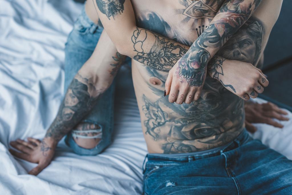 vue recadrée de petite amie embrassant son petit ami tatoué au lit
 - Photo, image