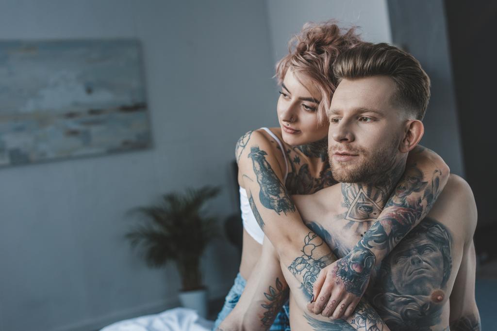 young girlfriend hugging her tattooed boyfriend in bed - Photo, Image