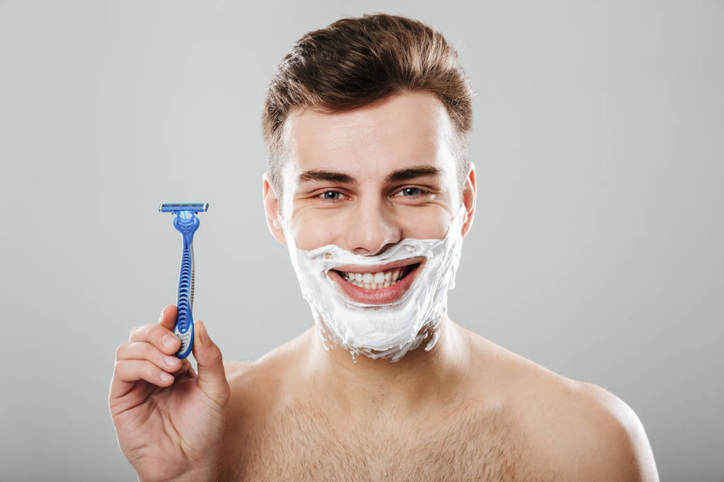Положительные эмоции молодого привлекательного парня во время бритья с Ра
 - Фото, изображение