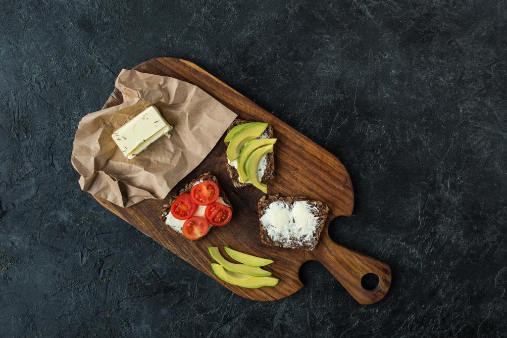 vlakke leggen met snacks voor gezond ontbijt op houten snijplank op donkere tafelblad - Foto, afbeelding