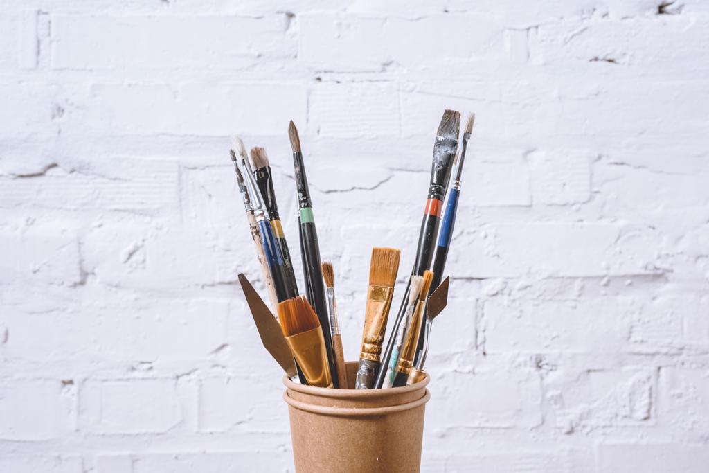 paint brushes in paper cups on white wall - Photo, Image
