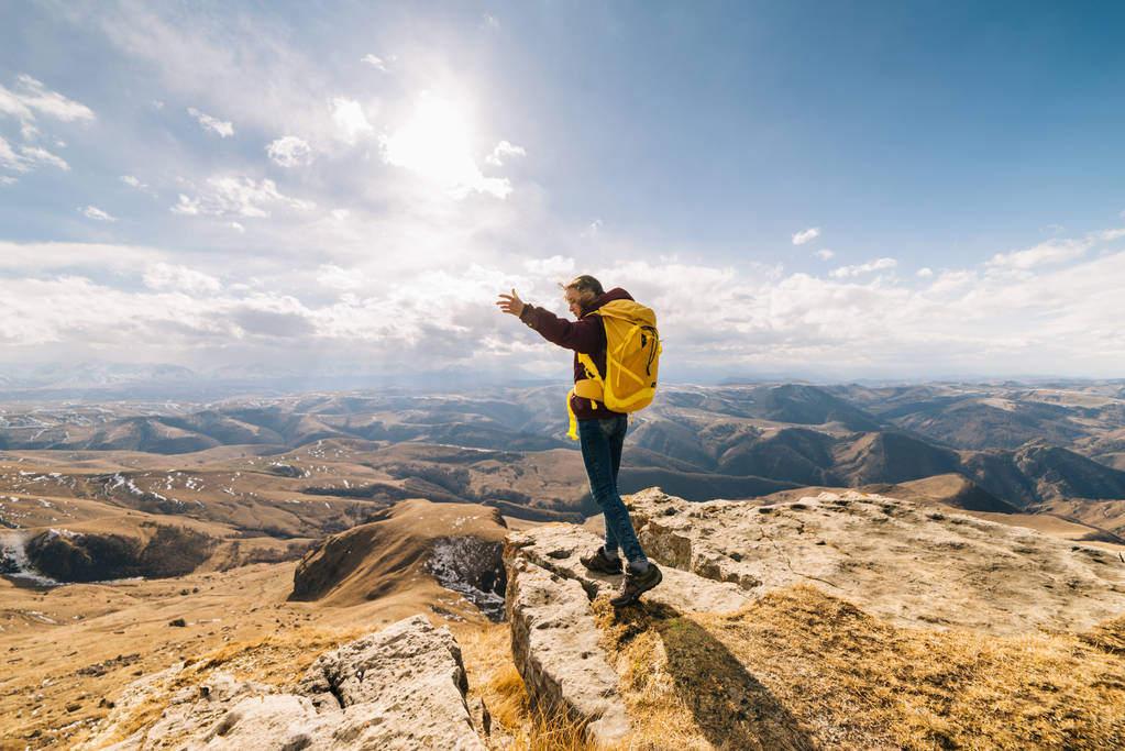 активна молода дівчина подорожує горами з жовтим рюкзаком, насолоджується сонцем
 - Фото, зображення