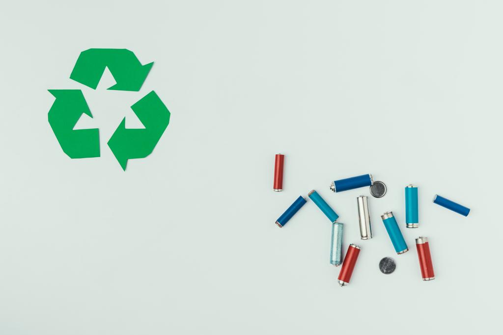 vista superior del cartel de reciclaje y varios tipos de baterías aisladas en gris
 - Foto, imagen