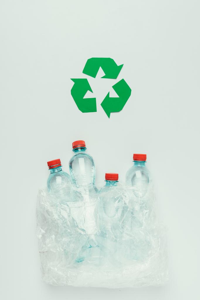 top view of recycle sign and plastic bottles in plastic bag isolated on grey - Photo, Image