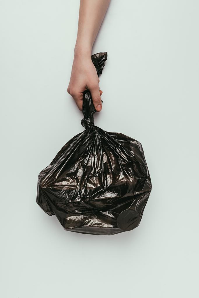 abgeschnittene Aufnahme einer Frau mit Müllsack in der Hand isoliert auf grau - Foto, Bild