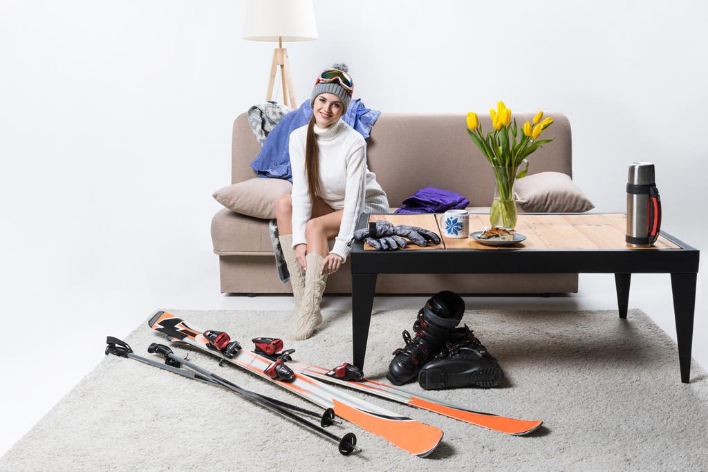 молода спортсменка в теплих шкарпетках, лижне обладнання поруч
 - Фото, зображення