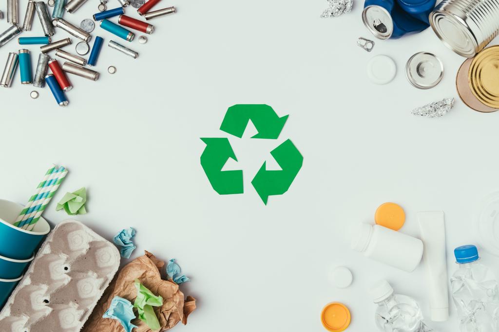 flache Liege mit arrangierten verschiedenen Müllarten und Recyclingschild isoliert auf grau - Foto, Bild