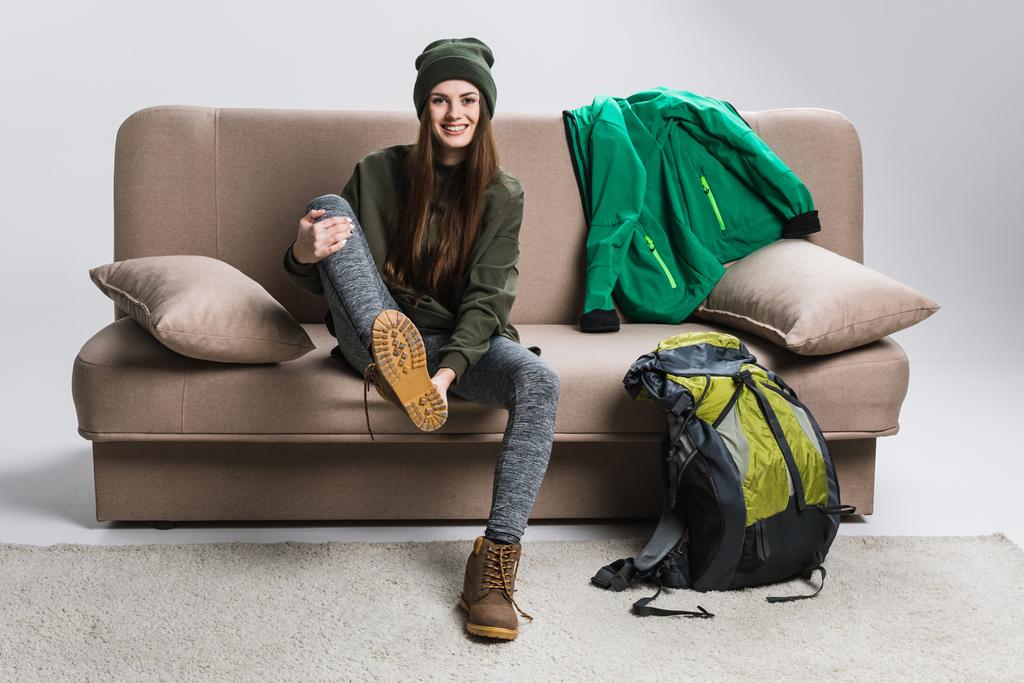 beautiful traveler wearing hiking boots and warm clothing on sofa - Photo, Image