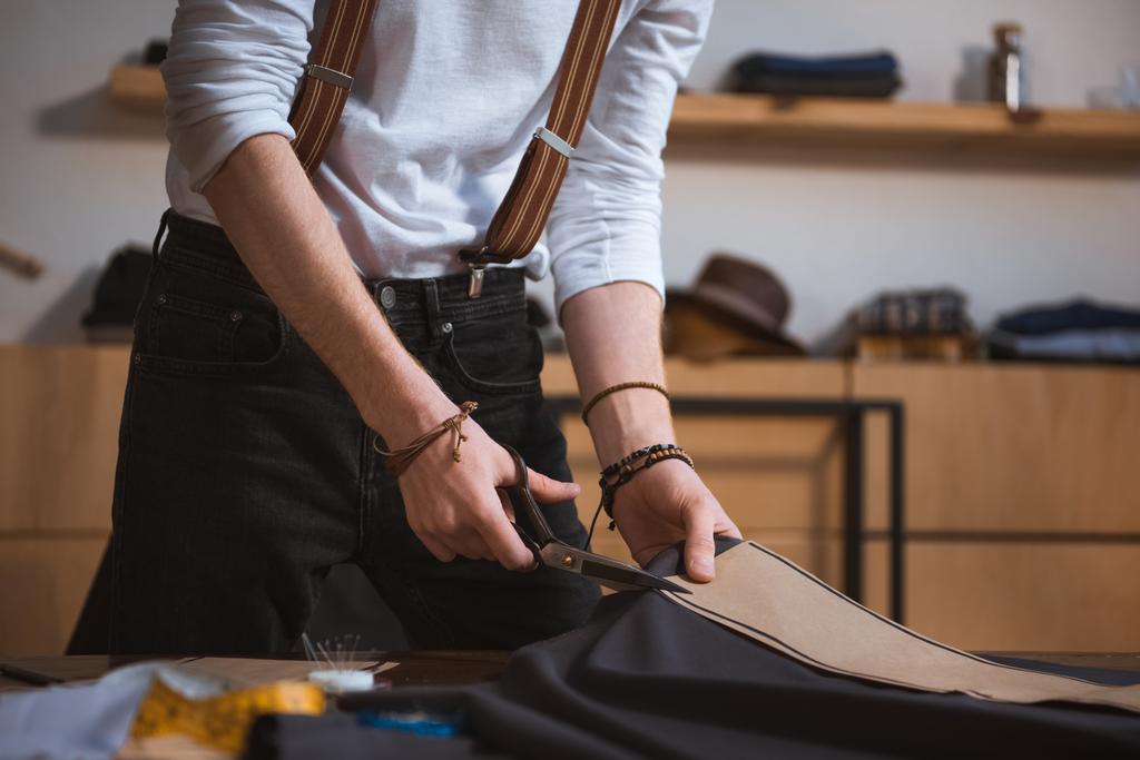 обрезанный снимок мужчины модельера, работающего с ножницами, узорами шитья и тканями
  - Фото, изображение