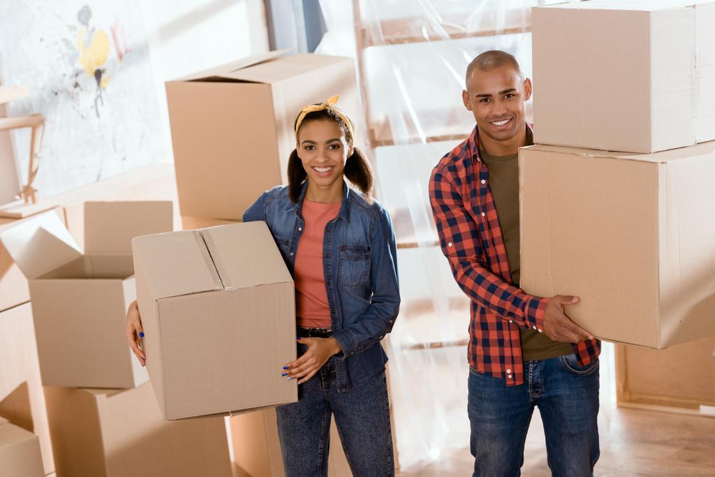 hermosa pareja afroamericana sosteniendo cajas de cartón y mudarse a un nuevo hogar
 - Foto, imagen