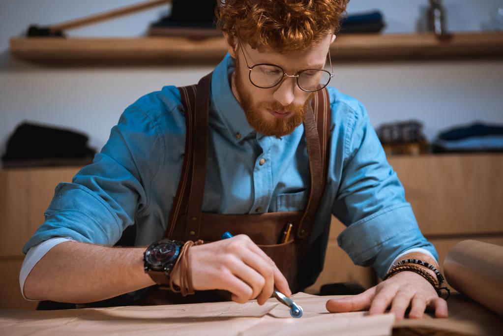 keskittynyt nuori mies muotisuunnittelija silmälasit tehdä ompelu kuvioita työpaikalla
 - Valokuva, kuva