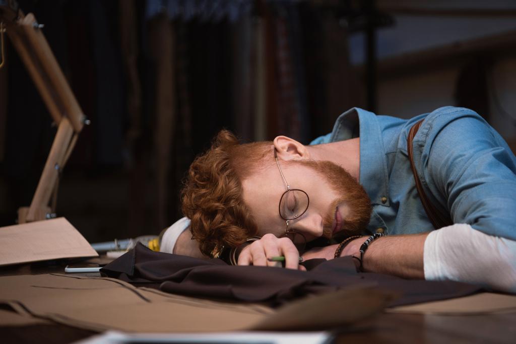 fatigué jeune créateur de mode dans des lunettes dormir sur la table sur le lieu de travail
 - Photo, image