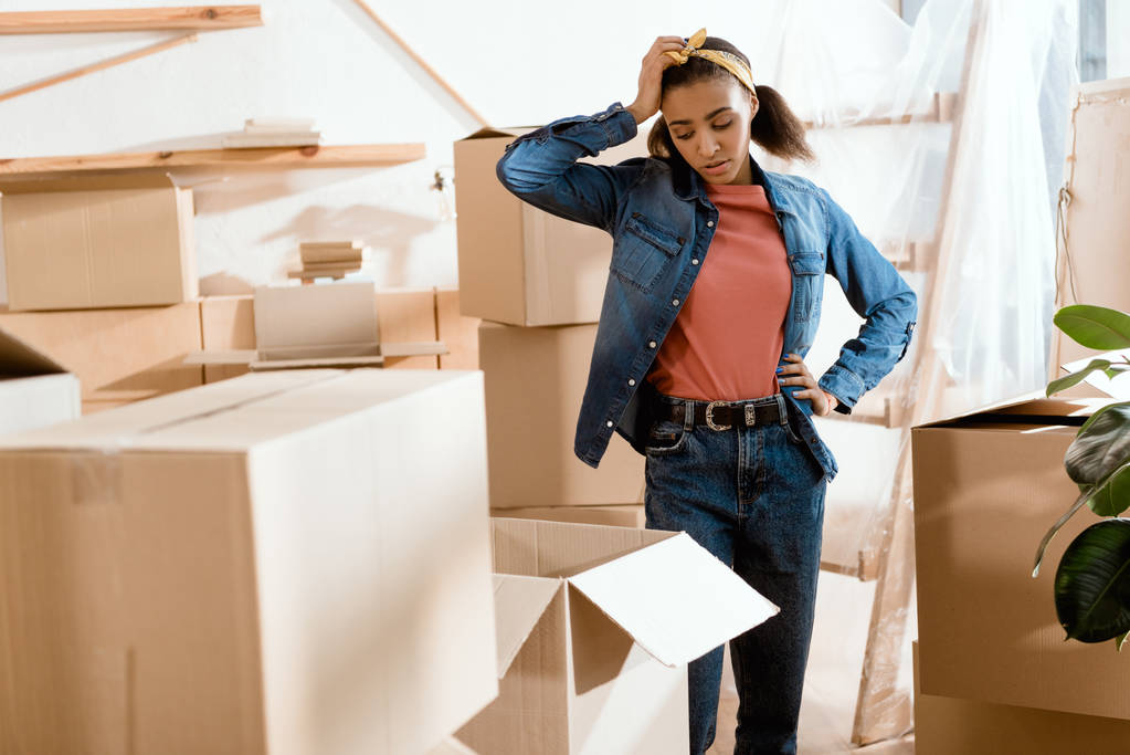 upset tired african american girl unpacking cardboard boxes in new home - Photo, Image