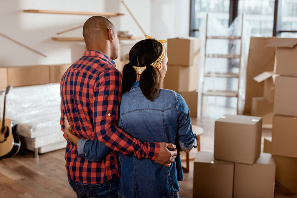 vista trasera de pareja afroamericana mirando a nuevo hogar con cajas de cartón
 - Foto, imagen