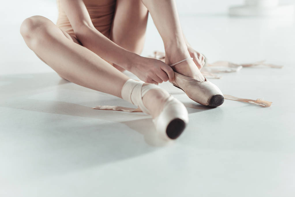 Bela pequena bailarina colocando em pé sapatos pointe
 - Foto, Imagem