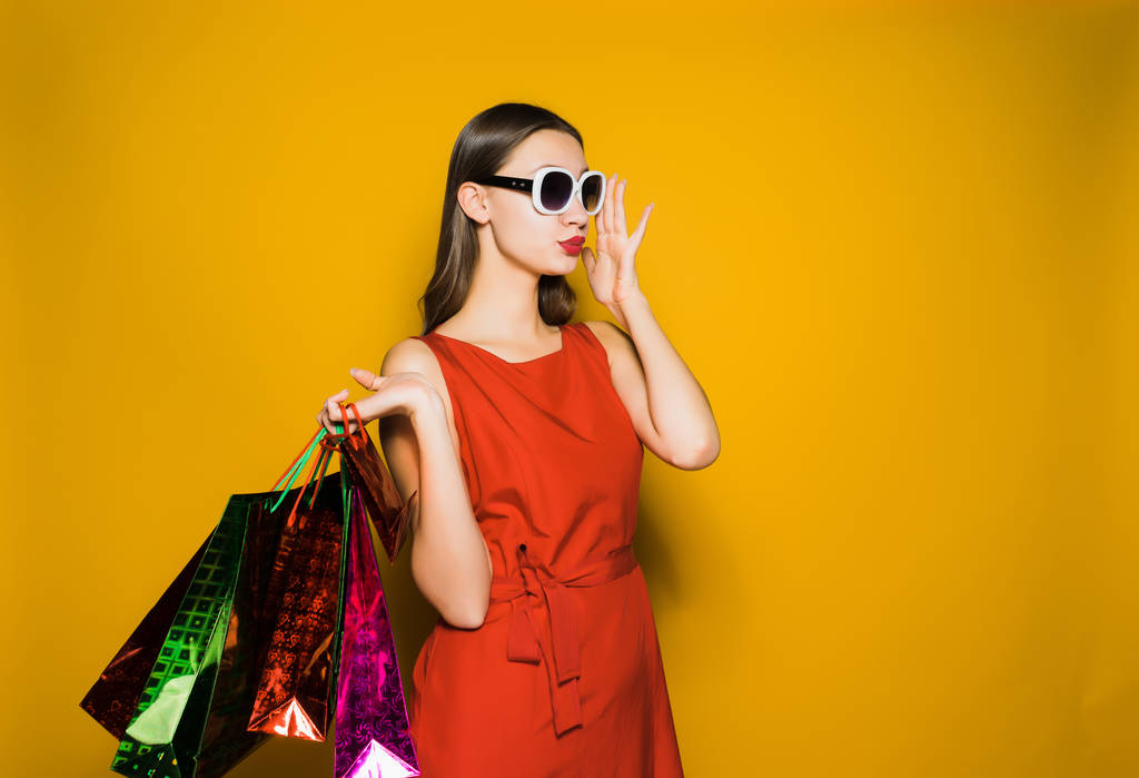 стильная молодая девушка в красном платье и солнечные очки пошли по магазинам в черную пятницу
 - Фото, изображение