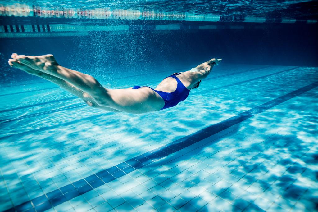 underwater picture of young female swimmer exercising in swimming pool - Photo, Image
