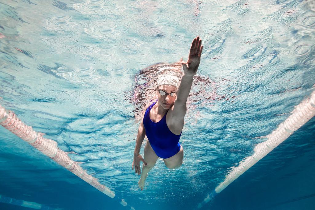 Unterwasserbild einer Schwimmerin in Badeanzug und Brille beim Training im Schwimmbad - Foto, Bild