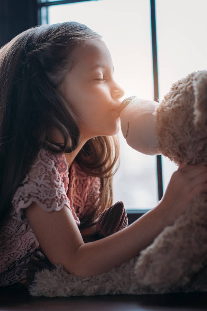 schönes kleines Kind küsst Teddybär in die Nase - Foto, Bild