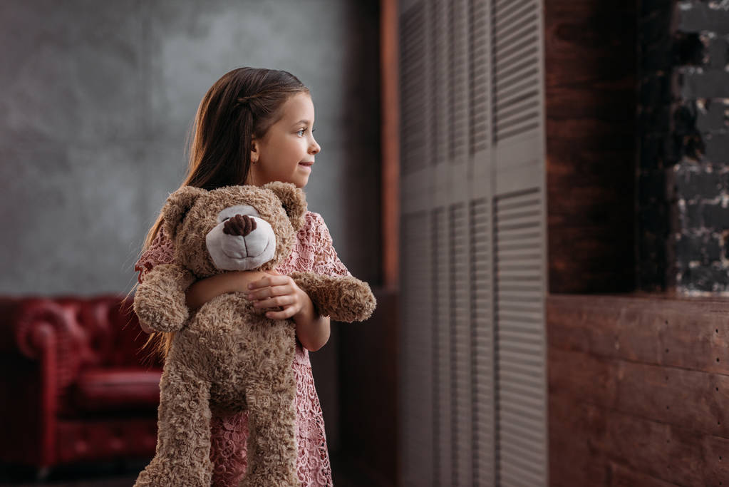 mooi klein kind thuis houden van teddybeer - Foto, afbeelding
