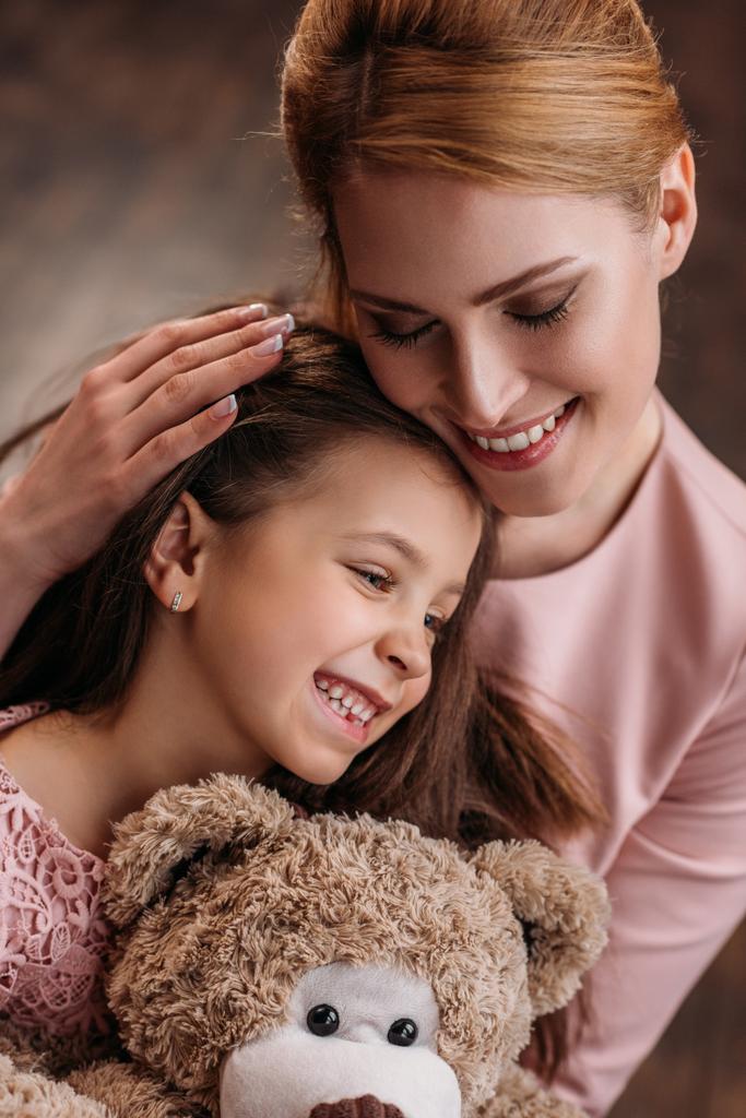 close-up tiro de mãe abraçando sua filha enquanto ela segurando ursinho de pelúcia
 - Foto, Imagem
