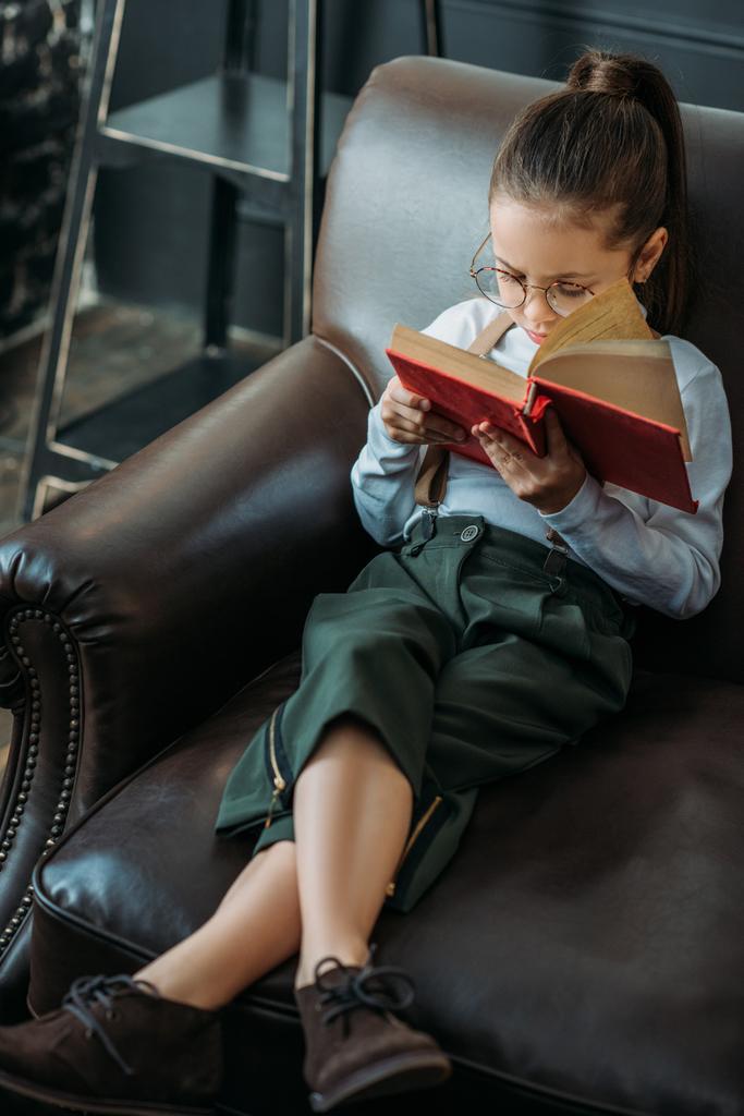 wysoki kąt widzenia adorable little dziecko czytanie książki na kanapie w domu - Zdjęcie, obraz