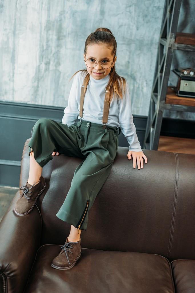 adorable little child in stylish clothing sitting on couch in loft apartments - Photo, Image