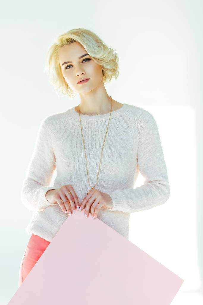 красивая блондинка с розовым плакатом и глядя на камеру на сером
  - Фото, изображение