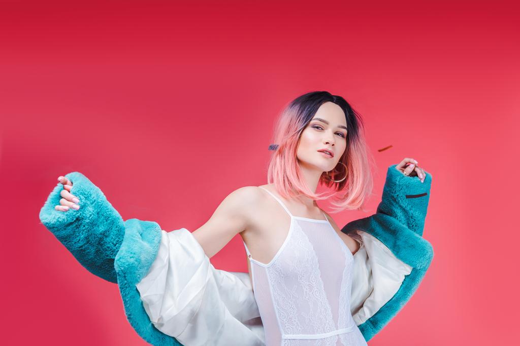 fashionable girl with pink hair posing in lace bodysuit and blue fur coat, isolated on pink - Photo, Image