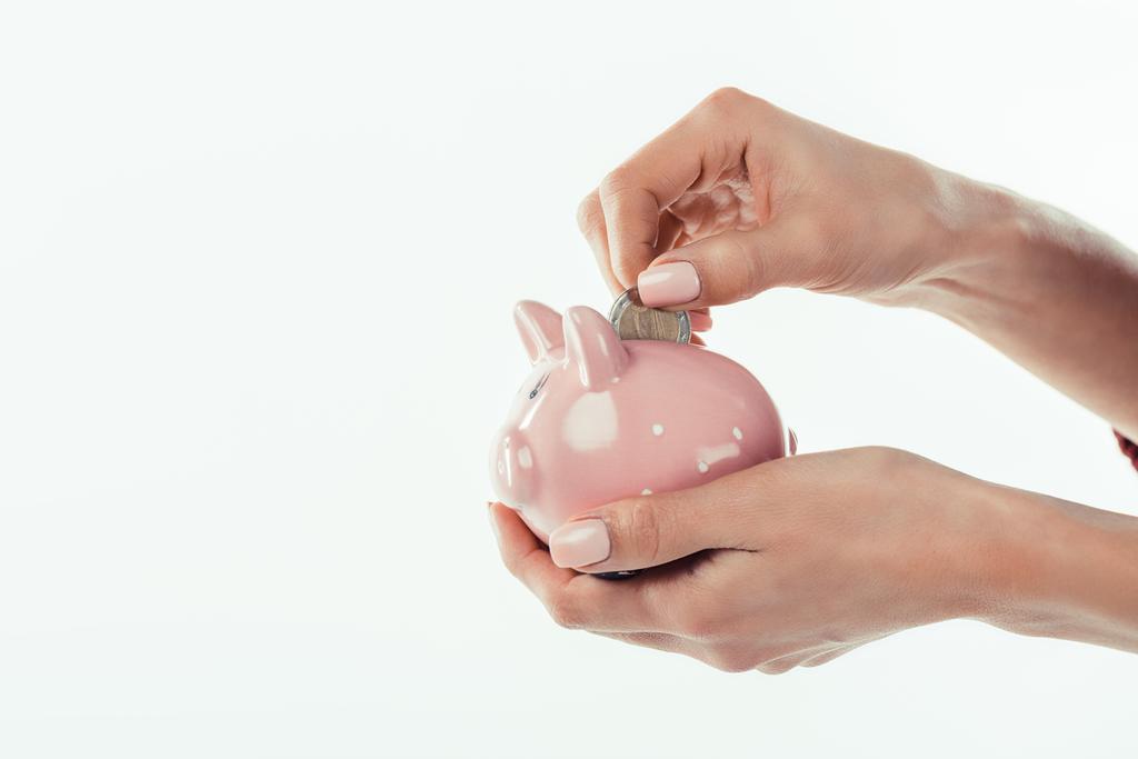 cropped view of woman putting coin into little piggy bank, isolated on white - Photo, Image