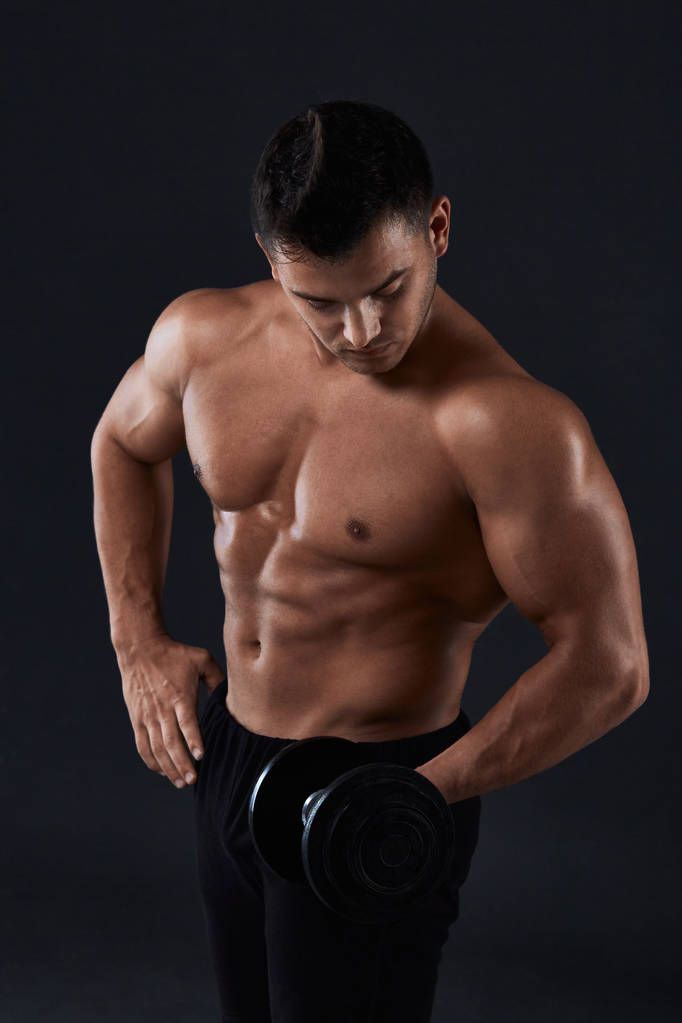 Gespierde bodybuilder doen oefeningen met dumbbell over zwarte ba - Foto, afbeelding