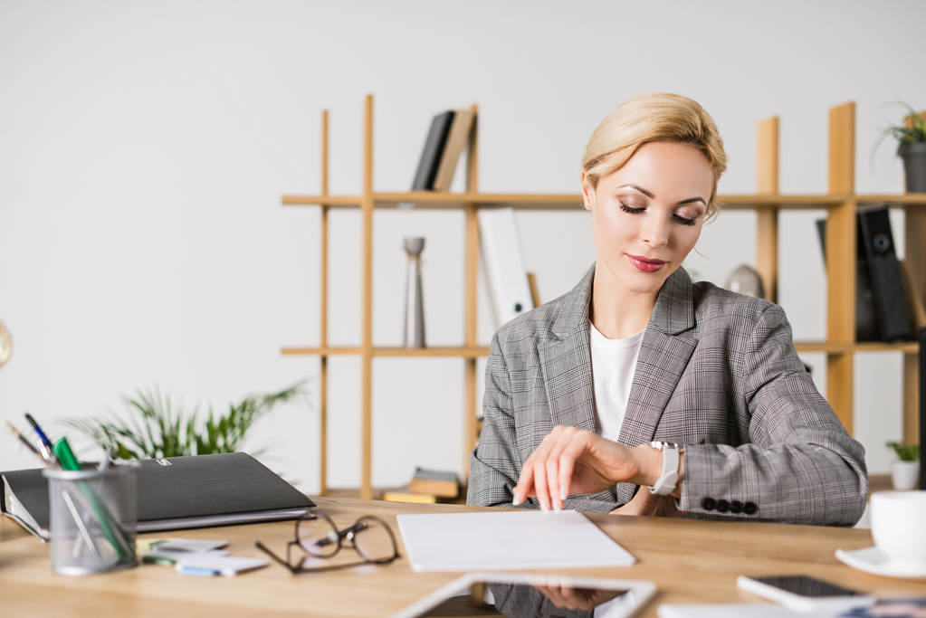 portrait of businesswoman checking time at workplace in office - Photo, Image