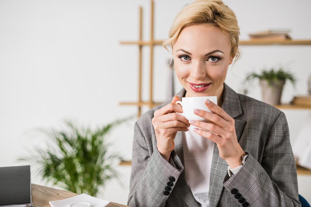 portrait de joyeux belle femme d'affaires avec tasse de café en regardant la caméra
 - Photo, image