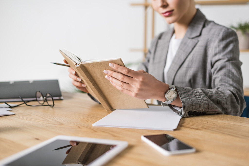 обрізаний знімок бізнес-леді з ноутбуком, що сидить на робочому місці в офісі
 - Фото, зображення