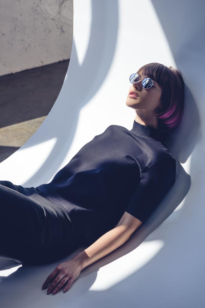 stijlvolle meisje liggend in zwarte kleding en zonnebril  - Foto, afbeelding