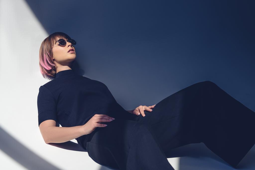 stílusos lány, fekvő, fekete ruhát és napszemüveg  - Fotó, kép