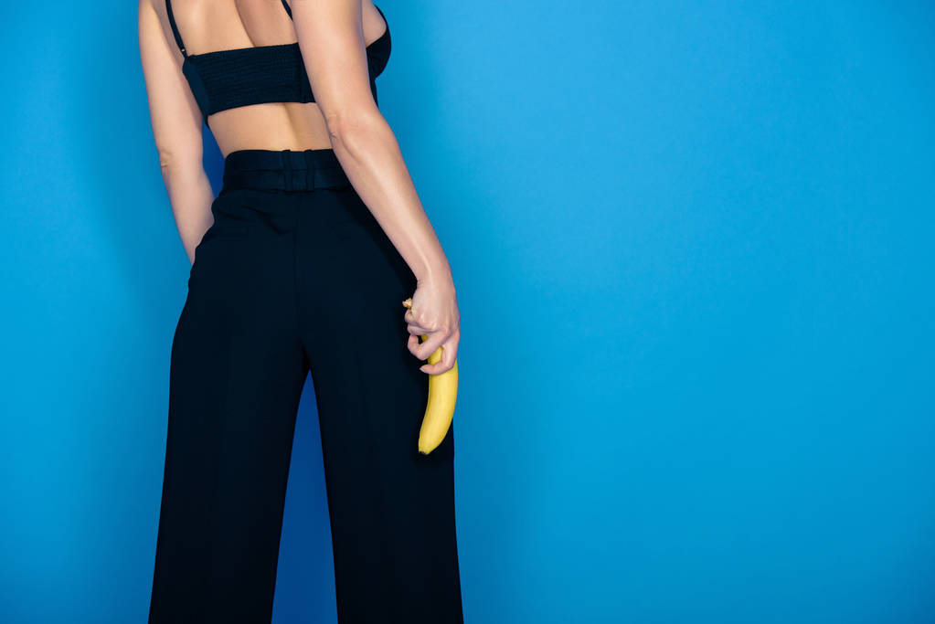 oříznutý obraz stylová holka drží banán izolované na modré - Fotografie, Obrázek
