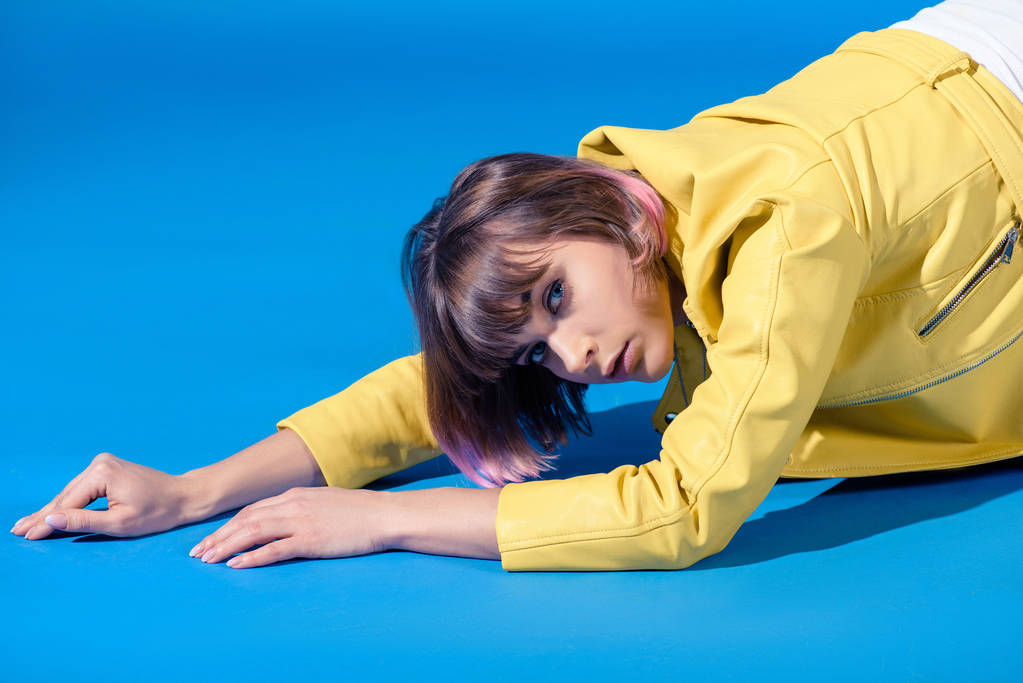 viettelevä tyylikäs tyttö makaa keltainen nahka takki ja katsot kameran sininen
 - Valokuva, kuva